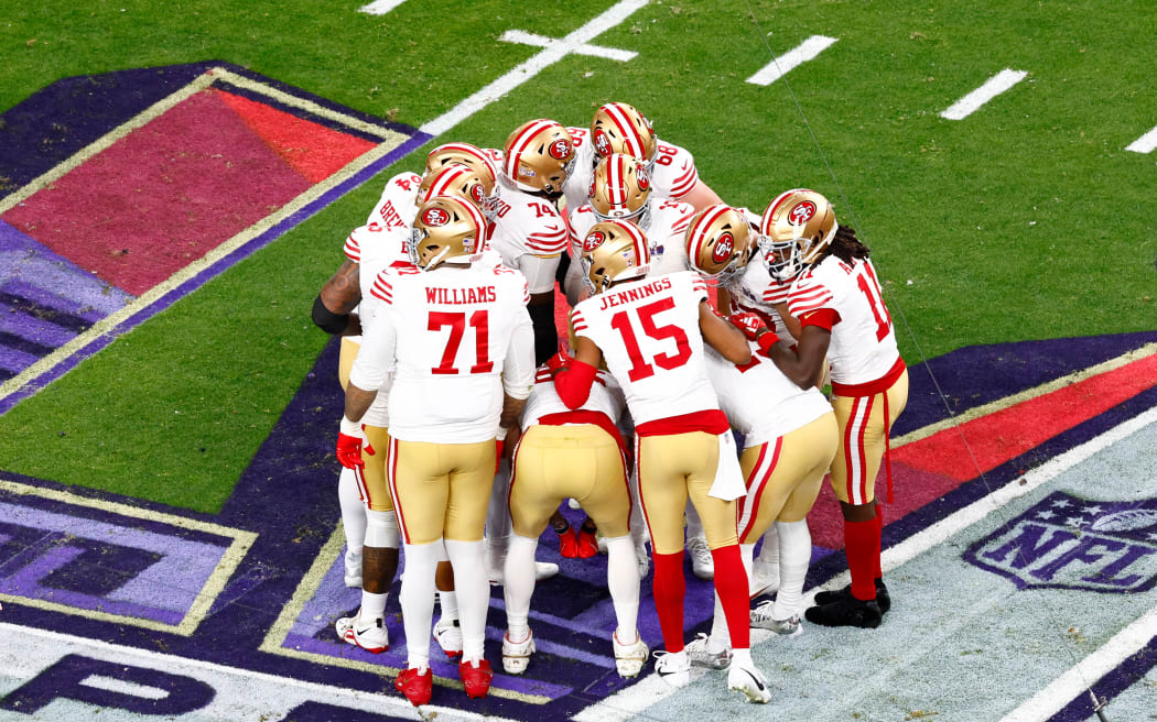 San Francisco 49ers players in a huddle.