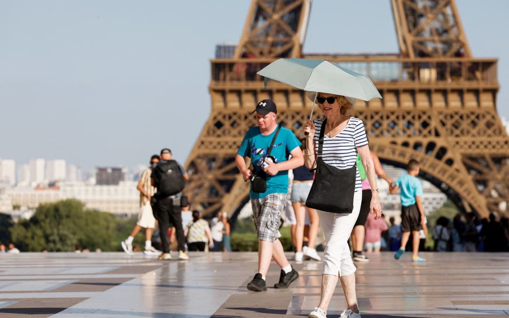A tourist holds an umbrella as protection from the sun during a heatwave near the Eiffel Tower, in Paris, on June 30, 2025. French authorities put Paris on red alert for extreme heat.