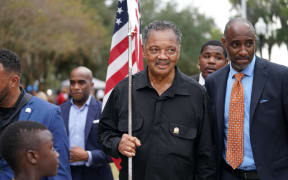 Rev. Jesse Jackson carries an American flag outside the Glynn County Courthouse, where three white men are on trial for the murder of Ahmaud Arbery.