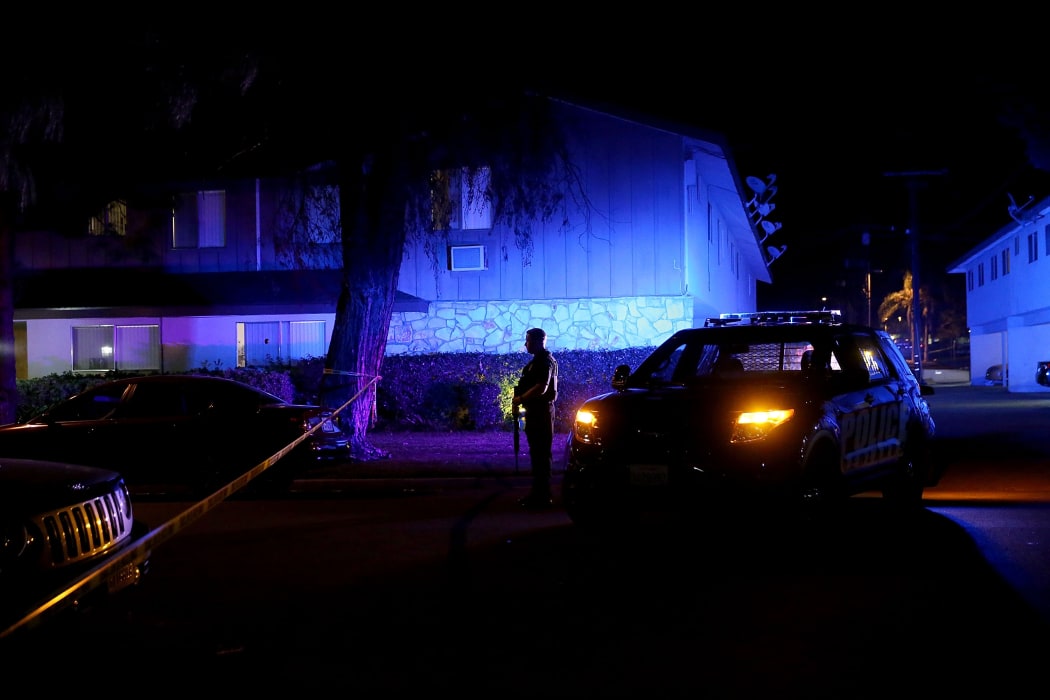 A police officer stands guard during an investigation of a suspicious vehicle on 2 December in Redlands, California.