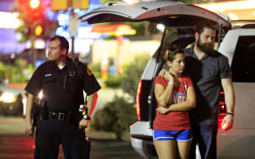 Dallas police and residents stand near the scene where four Dallas police officers were shot and killed on July 7, 2016 in Dallas, Texas.