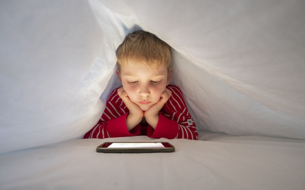 Boy in his bed using smartphone to make a video call. (Photo by CONCEPTUAL IMAGES/SCIENCE PHOTO / PHR / Science Photo Library via AFP)