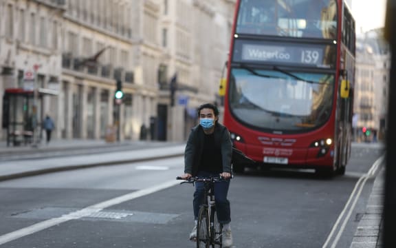 A man wearing a face mask as a preventive measure against the coronavirus (Covid-19) pandemic rides his bike in central London, England on May 5, 2020.