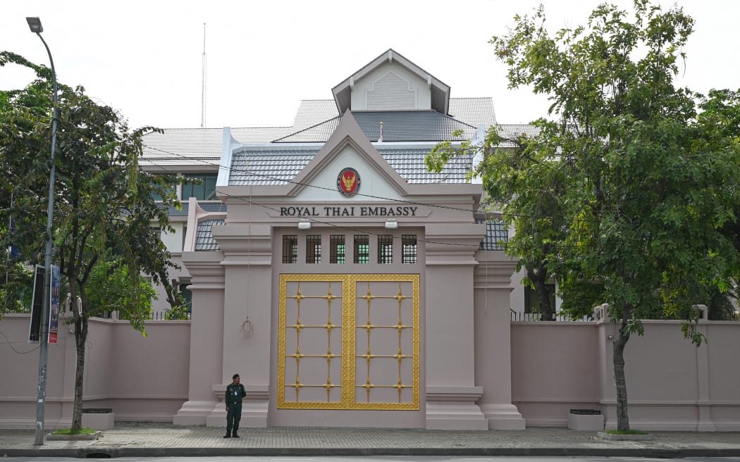 A Cambodian police officer stands guard in front of the Thai embassy in Phnom Penh on July 24, 2025. Cambodian and Thai troops exchanged fire in a new round of clashes at a disputed border area on July 24, 2025, both sides said. (Photo by TANG CHHIN Sothy / AFP)