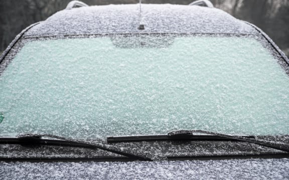 frozen windshield of a car with ice and snow, concept of traffic risks in winter, copy space, selected focus