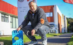 Businessman Bryce Cole displays a shredded water main cover and a piece of tyre left by "hoons" using Birch Ave in Judea as a burnout pad.
