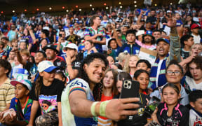 Dallin Watene-Zelezniak of the Warriors takes a selfie with fans.