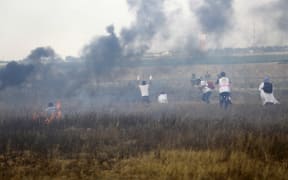 Palestinian paramedics approach the barbed wire fence with Israel to tend to injured protesters during clashes along the border east of Khan Yunis in the southern Gaza strip on June 1, 2018.