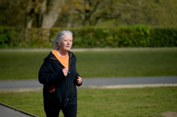 Older woman taking a run in a park.