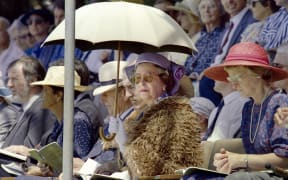 British Queen Elizabeth II (C), shielding herself from the sun with an umbrella, listen to a speech by Anglican Archbishop Hui Vercoe during the celebrations of New Zealand's 150th anniversary in Waitangi on February 6, 1990.