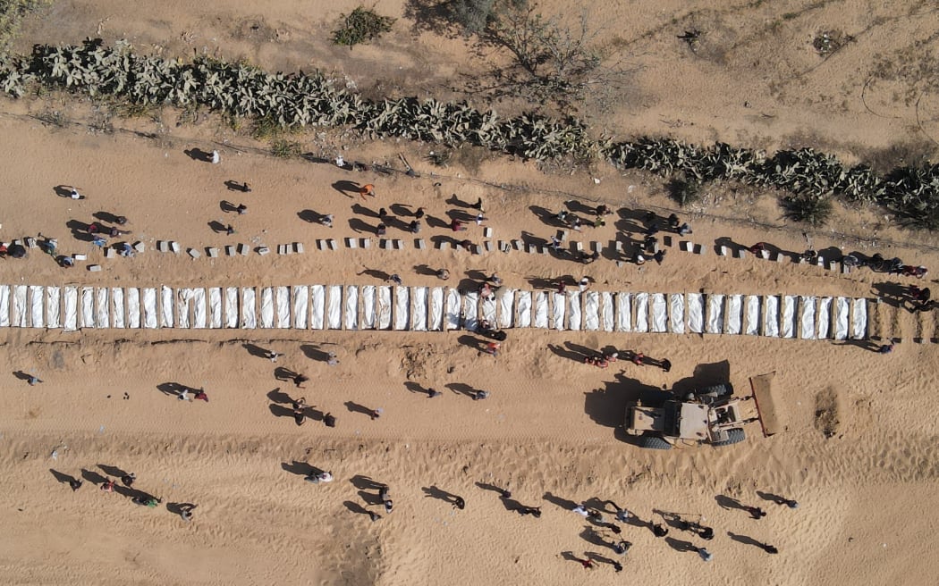 This aerial view shows Palestinians burying 54 unidentified bodies in a cemetery in Deir al-Balah, in the central Gaza Strip, on October 22, 2025, after they were returned by Israel under a US-brokered ceasefire deal.
