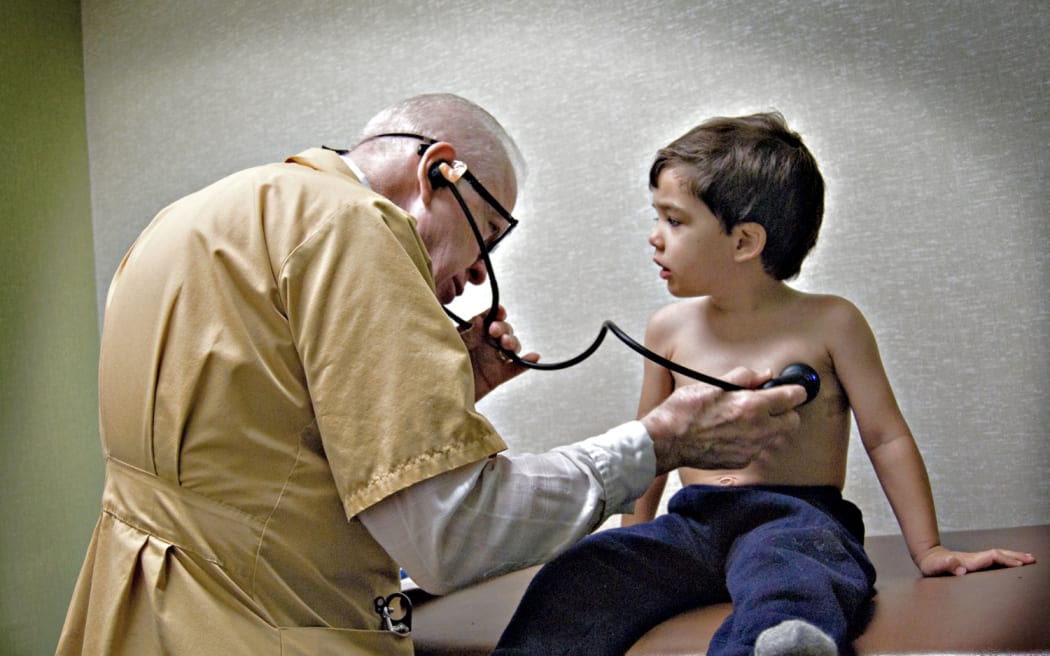 Doctor examining small boy with stethoscope