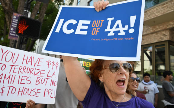 Protestors holding signs reading "ICE ot of LA!" march in front of the AC Hotel Pasadena on June 8, 2025, in Pasadena, California, as they believe ICE agents are staying at this hotel. US President Donald Trump deployed 2,000 troops on June 7 to handle escalating protests against immigration enforcement raids in the Los Angeles area, a move the state's governor termed "purposefully inflammatory." Federal agents clashed with angry crowds in a Los Angeles suburb as protests stretched into a second night Saturday, shooting flash-bang grenades and shutting part of a freeway amid raids on undocumented migrants, reports said. (Photo by Robyn BECK / AFP)