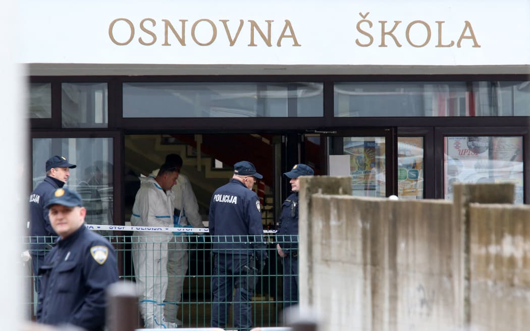 Police officers and emergency units stand at the entrance of the 