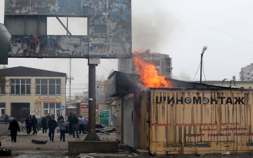 People look at a burning shop after shelling in the southern Ukrainian port city of Mariupol.