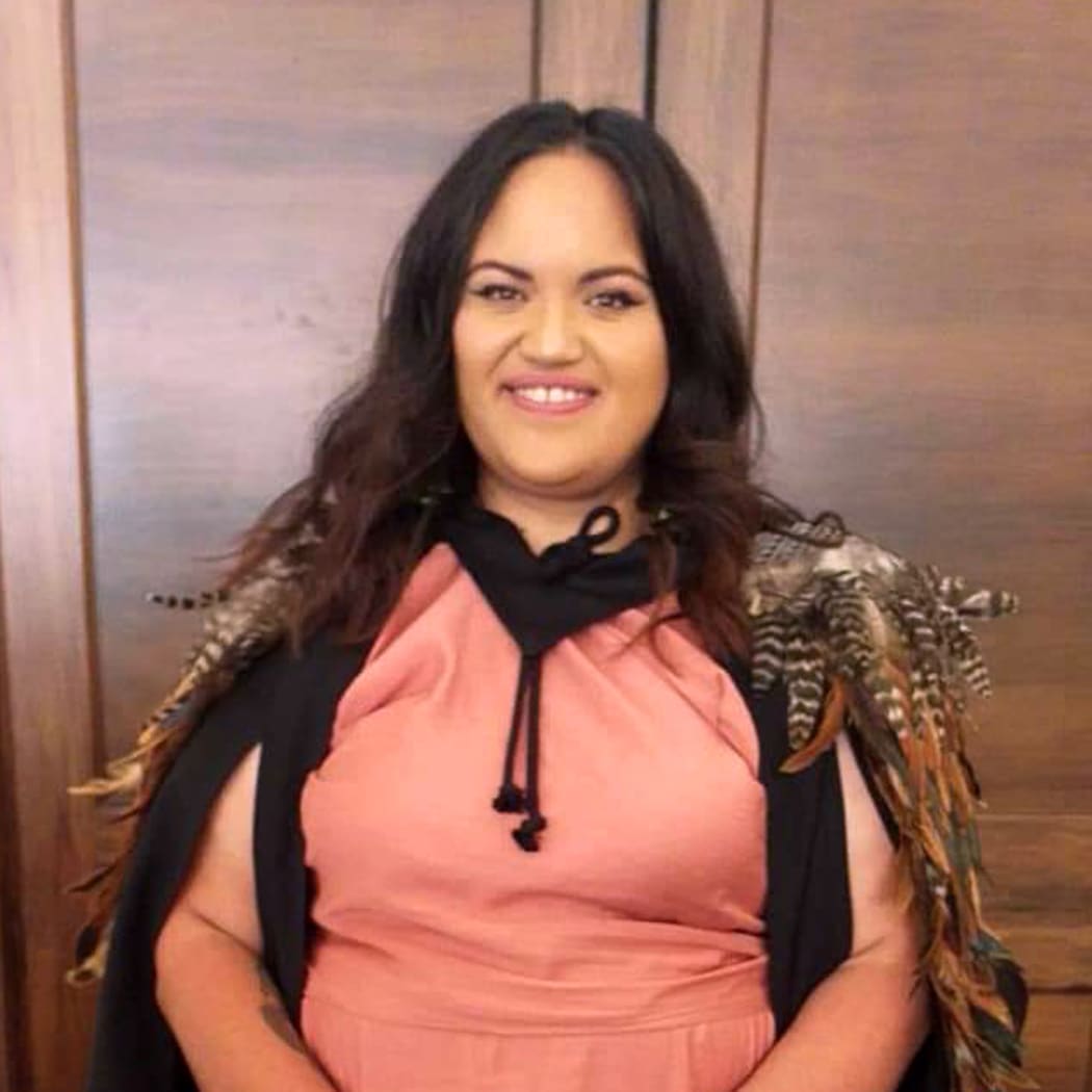 Early Childhood Education teacher Penina Ria stands smiling at the camera wearing a pink dress and Māori cloak at her graduation