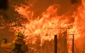 A firefighter watches as a building burns during the Mendocino Complex fire in Lakeport, California