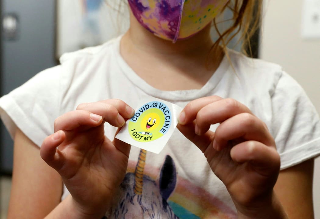 A 6-year-old child holds a sticker she received after getting the Pfizer-BioNTech Covid-19 vaccine at the Child Health Associates office in Novi, Michigan on 3 November 2021.