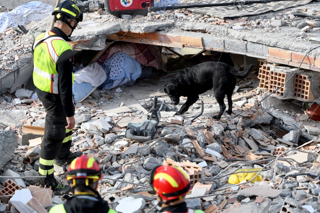 Italian rescuers search for survivors through the rubble of a collapsed building in Thumane.