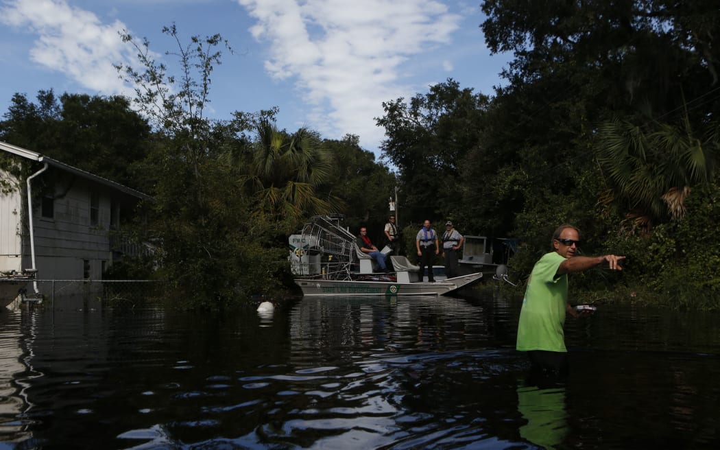 A resident points back to his home as he speaks with law enforcement officers using an airboat to survey damage around homes from high winds and storm surge associated with Hurricane Hermine.
