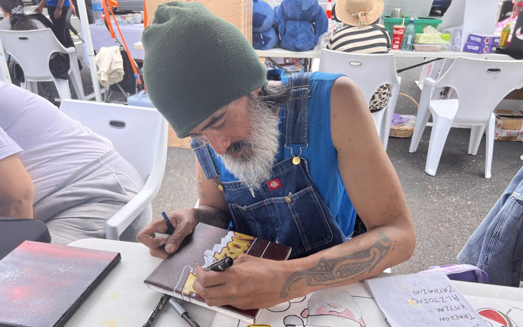 Loko from Loko Arts is creating his canvas art, his product that he sells as an entrepreneur.