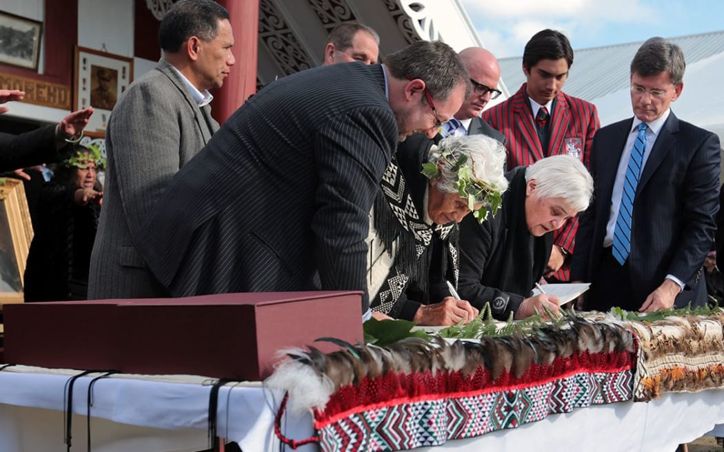 Te Tai Hauauru MP Tariana Turia (right) signs as Treaty Negotiations Minister Chris Finlayson looks on (far right).