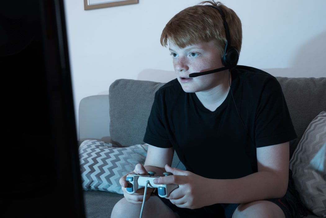 A photo of a boy with a Joystick Engrossed In Playing Videogames in a  darkened room at home
