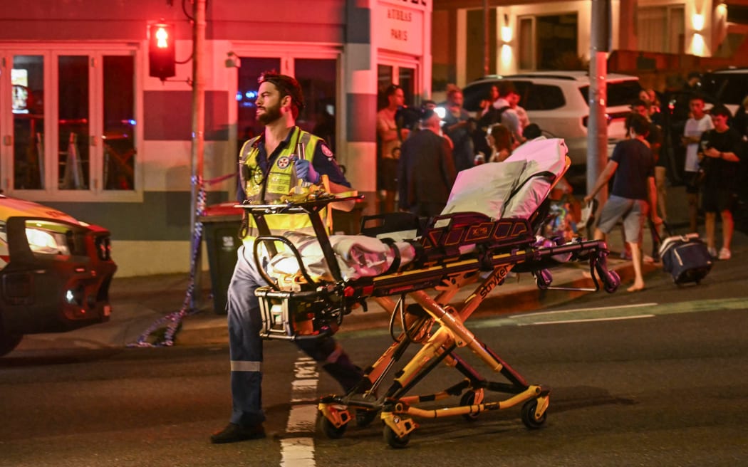 A health worker moves a stretcher after a shooting incident at Bondi Beach in Sydney on December 14, 2025. Australian police said two people were in custody following reports of multiple gunshots on December 14 at Sydney's famed Bondi Beach, urging the public to take shelter. (Photo by Saeed KHAN / AFP)