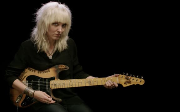 Cindy Hulej of Carmine Street Guitars holding a stratocaster style guitar