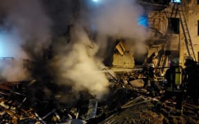 Firefighters extinguish a blaze at a damaged residential building at Koshytsa Street in the Ukrainian capital Kyiv, early on 25 February 2022.