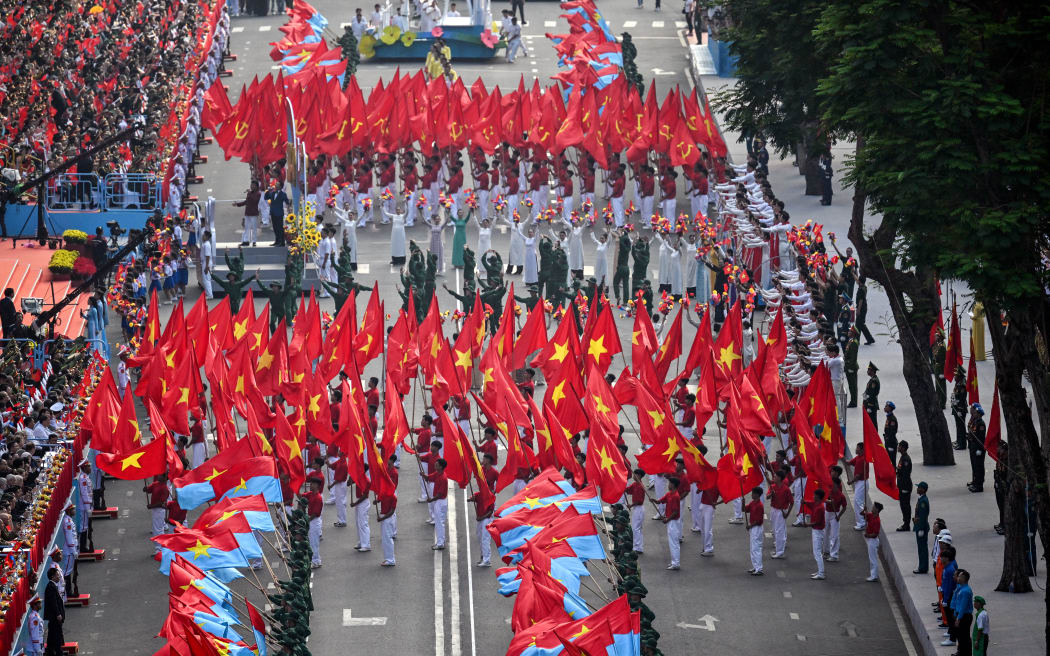 Participants wave flags as they march during a parade marking the 50th anniversary of the fall of Saigon.