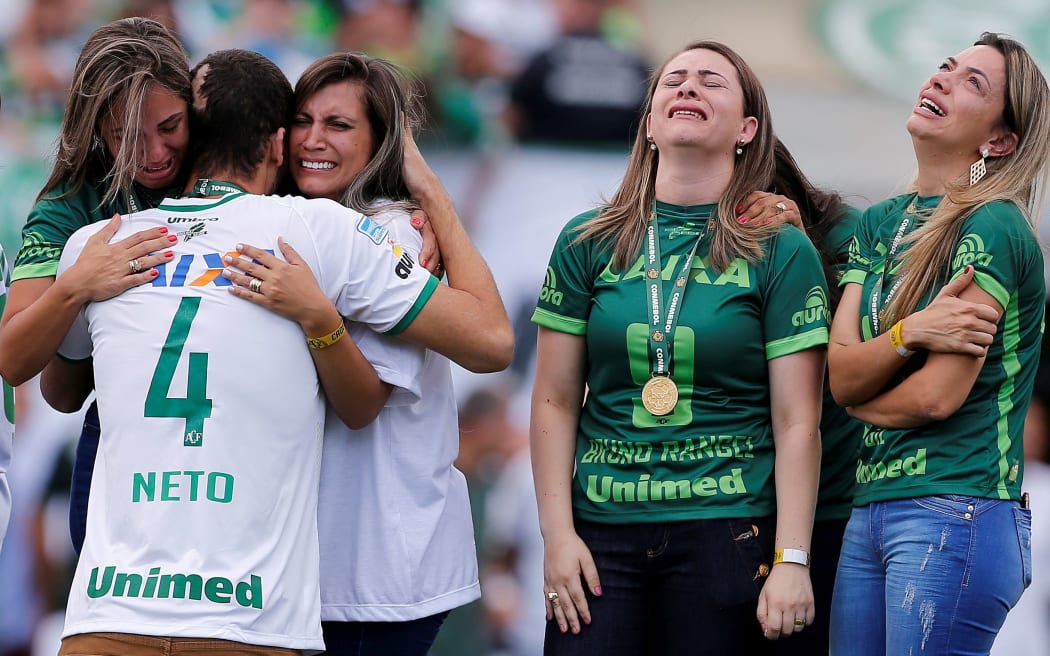 Neto a survivor of the crash embraces wives of dead players.