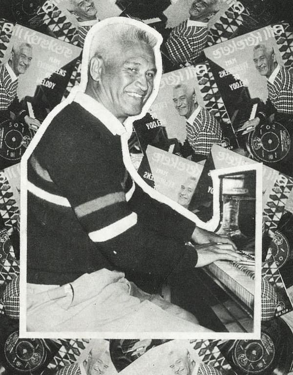 A white-haired man smiles while playing the piano.