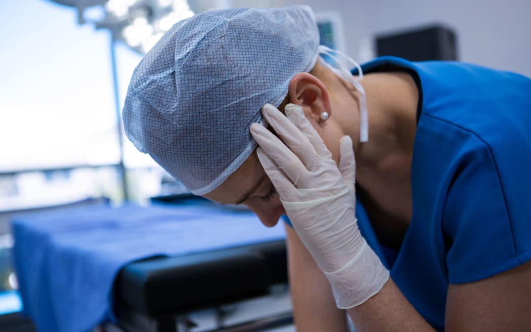 Sad female nurse sitting in operation theater at hospital