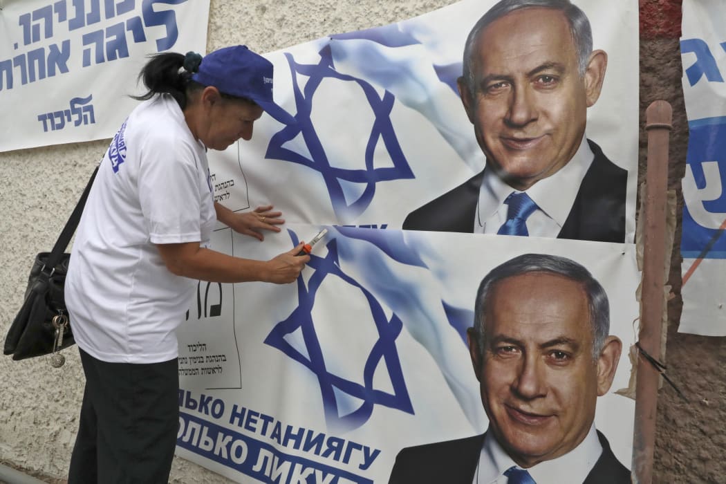 A woman places electoral banners for the Likud party showing Israeli Prime Minister Benjamin Netanyahu, in the southern Israeli city of Beersheva on 15 September 2019.