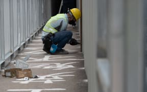 A construction worker uses metal sheeting to cover up one of the last public tributes in Hong Kong to the deadly 1989 Tiananmen Square crackdown which has adorned a campus footbridge at the University of Hong Kong (HKU) for over three decades.