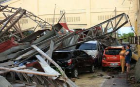 Residents stand next to cars damaged after a gymnasium collapsed at the height of super Typhoon Goni after it hit Tabaco, Albay province, south of Manila on November 1, 2020.