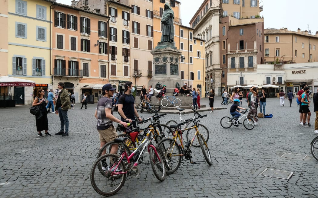 People ride their bicycle at in the Campo di Fiori square in central Rome on May 16, 2020 during the country's lockdown aimed at curbing the spread of the COVID-19 infection