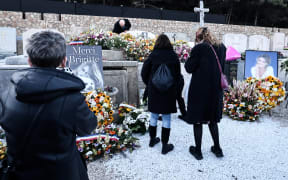 Well-wishers arrive to lay wreath of flowers and photographs to pay a tribute to late French actress Brigitte Bardot at her grave at the marine cemetery, following the funeral ceremony at Notre-Dame de l'Assomption church, in Saint-Tropez, southeastern France, on January 7, 2026.
