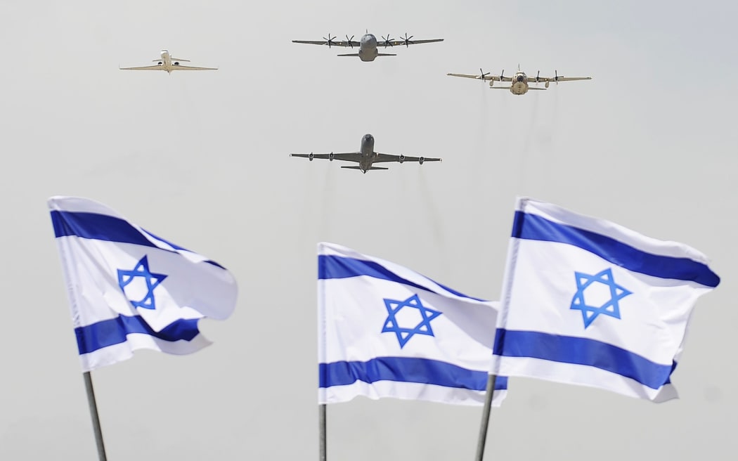 A new air force military cargo plane flies with Israeli military planes over Israeli flags in April 2014.