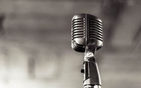 Black and white picture of an old 1960s style microphone on a stand
