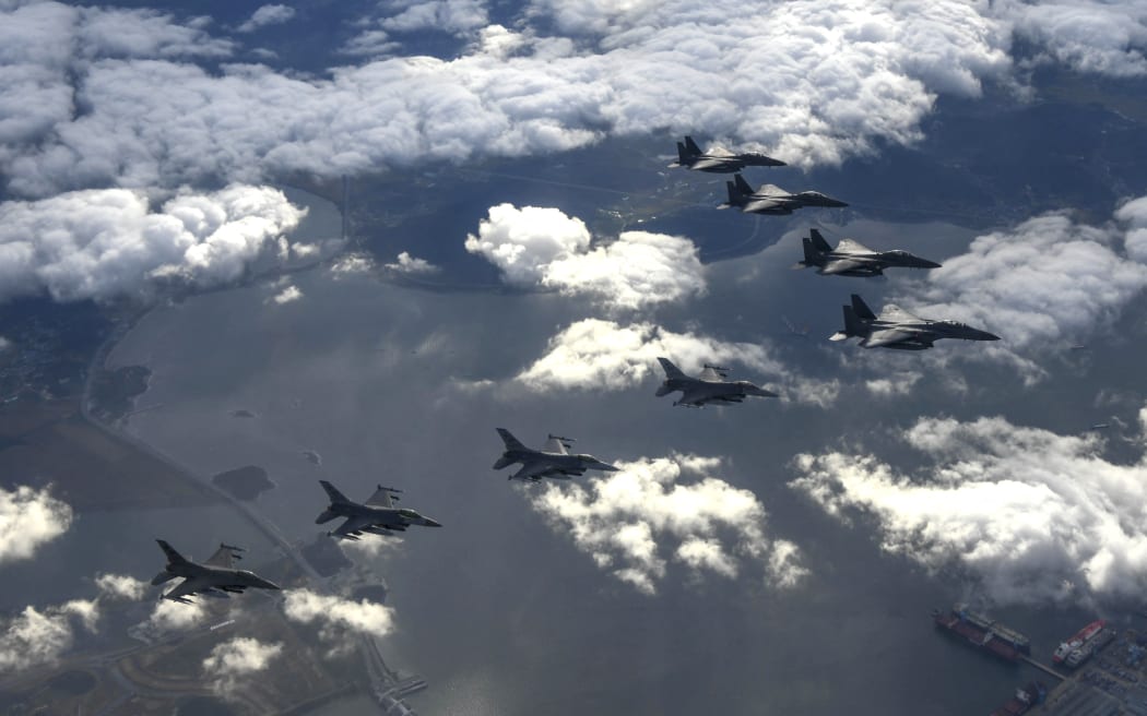 Four South Korean Air Force F-15Ks and four US Air Force F-16 fighters flying over South Korea, during a precision bombing drill in response to North Korea firing an Intermediate Range Ballistic Missile over Japan.
