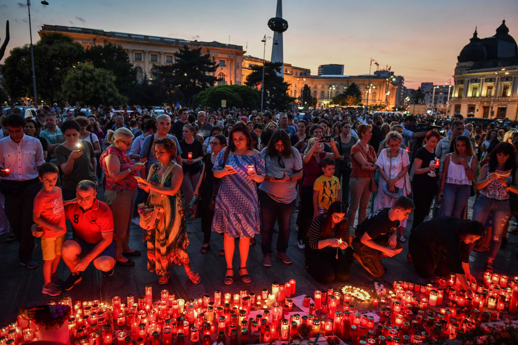 People light candles at a makeshift memorial site in front of the Romanian Ministry of Interior in Bucharest July 27, 2019 to commemorate Alexandra, the 15-year-old girl who has being murdered after she telephoned three times to report her own kidnapping.