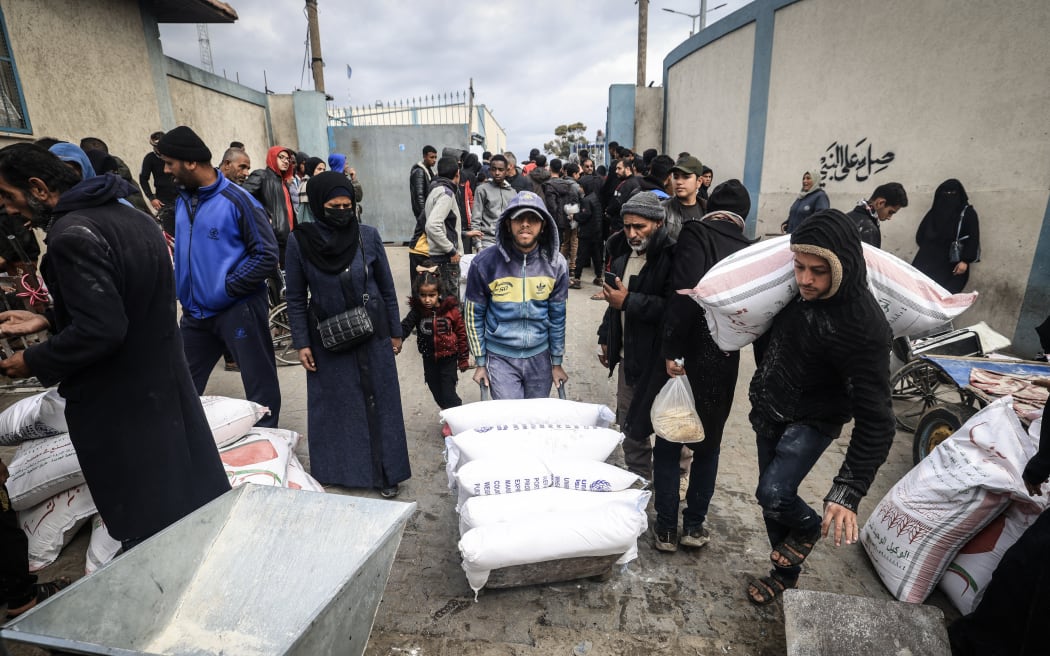 Displaced Palestinians receive food aid at the United Nations Relief and Works Agency for Palestine Refugees (UNRWA) center in Rafah in the southern Gaza Strip on January 28, 2024, amid ongoing battles between Israel and the Palestinian militant group Hamas. Israel has alleged several UNRWA staff were involved in Hamas's October 7 attack, leading some key donor countries to suspend funding and the agency to fire several staff over the claims, in a row between Israel and UNRWA a day after the UN's International Court of Justice ruling on January 26 that Israel must prevent possible acts of genocide in the conflict and allow more aid into Gaza. (Photo by AFP)