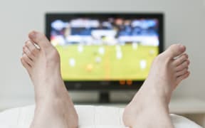 A person with their feet up watching sports on television.