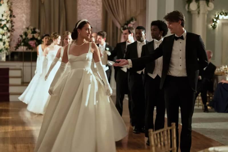 A young woman and man in formal attire do a group dance.