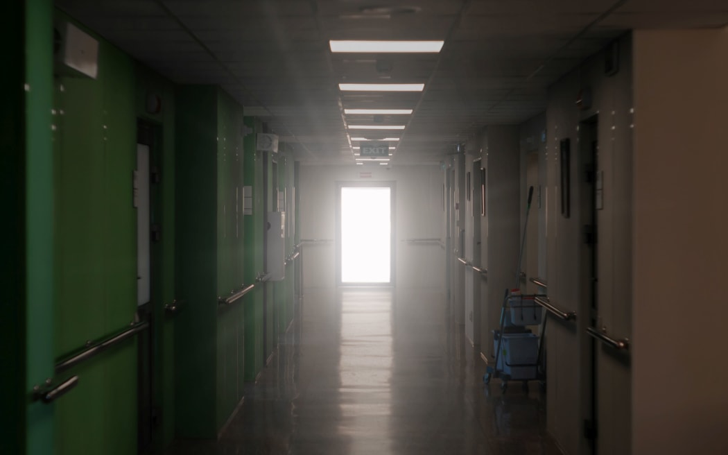 blurred dark hospital corridor with a luminous door at its end - an allegory of clinical death