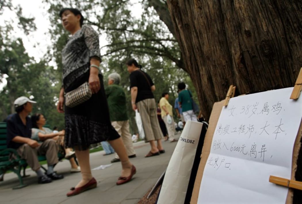 A Chinese parent walks past a board displaying a notice for a "to be married" 38 years old woman.