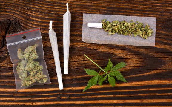 50549923 - marijuana background. cannabis joint, bud in plastic bag and hemp leaves on wooden table. addictive drug or alternative medicine.