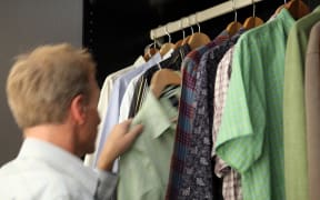 Man taking shirt from wardrobe (Photo by Simon Battensby / Image Source / Image Source via AFP)